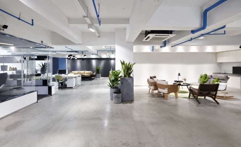 Commercial interior design for a Singapore office featuring polished concrete floors, glass partitioned workstations and lounge seating area
